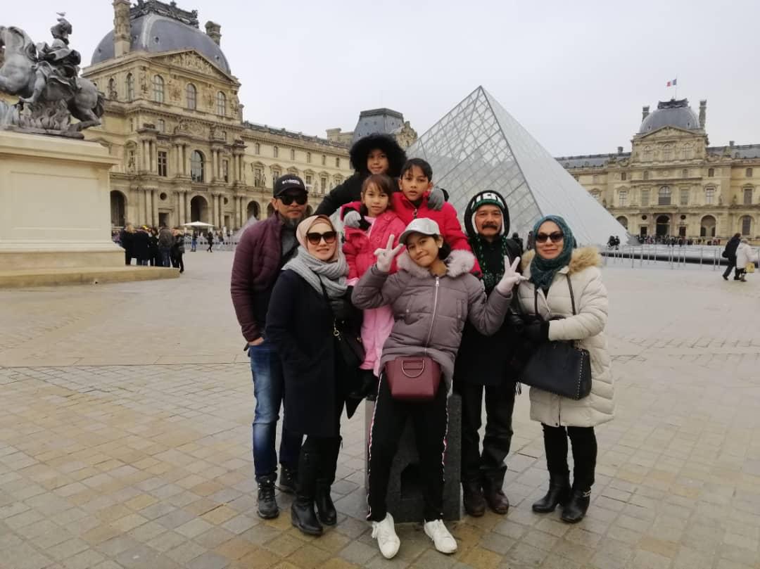 Kumpulan keluarga di hadapan piramid Louvre, Paris
